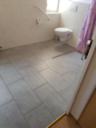 a bathroom with a toilet and a tile floor at Apartment im Fläming auch für Rollifahrer in Rietdorf