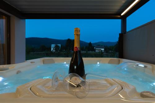a bottle of wine in a hot tub with glasses at Mountain Houses Volta in Lič