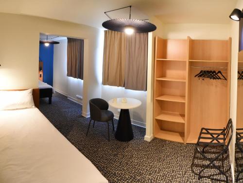 a room with a bed and a table and shelves at ibis Laval Le Relais D'Armor in Laval