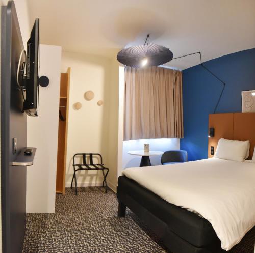 a hotel room with a bed and a blue wall at ibis Laval Le Relais D'Armor in Laval