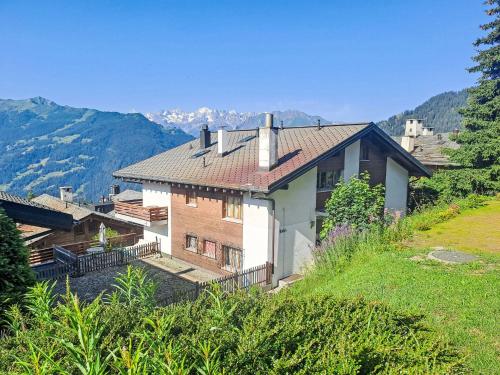 a house on a hill with mountains in the background at Apartment Porthos 37 by Interhome in Verbier