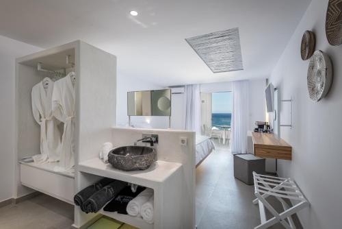 a white bathroom with a sink and a mirror at Kantouni Beach Boutique Hotel in Panormos Kalymnos