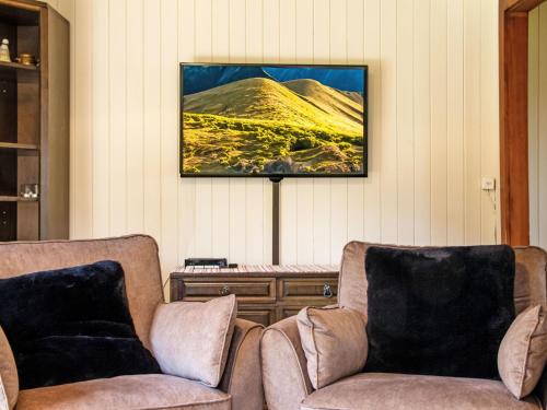 a living room with two chairs and a tv on the wall at Chalet Peer Gynt by Interhome in Nendaz