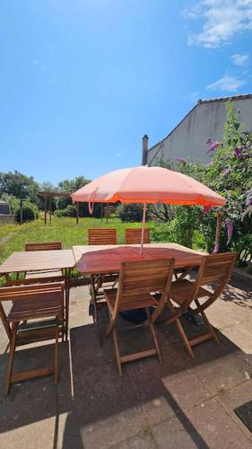 une table en bois avec des chaises et un parasol dans l'établissement La Fontaine gîte de charme à 12min du Puy duFou, à Sevremont