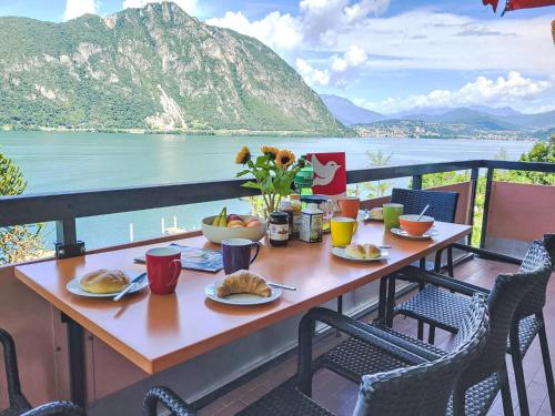 a table with food on a balcony with a view of the water at Apartment Frontlake Panorama Apt- 408 by Interhome in Bissone
