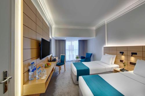 Lotus Grand Hotel في دبي: غرفة فندقية بسريرين وتلفزيون