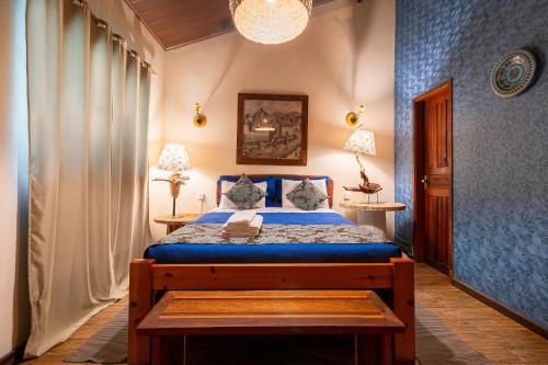 a bedroom with a bed with blue sheets and a blue wall at Pousada Do Lado de Lá in Pirenópolis