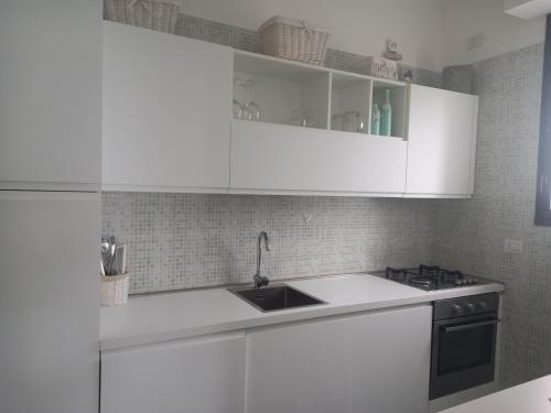 a kitchen with white cabinets and a sink at Anna e il mare in Cogoleto