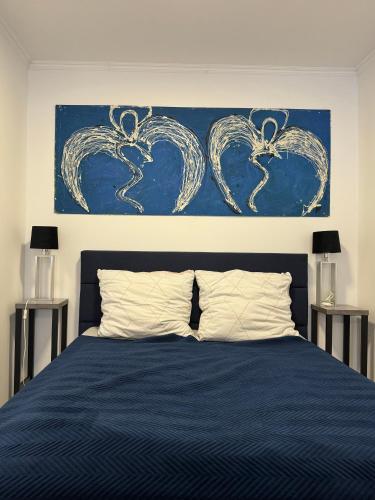 a bedroom with a blue bed with a painting on the wall at Apartament Arte Povera in Słubice