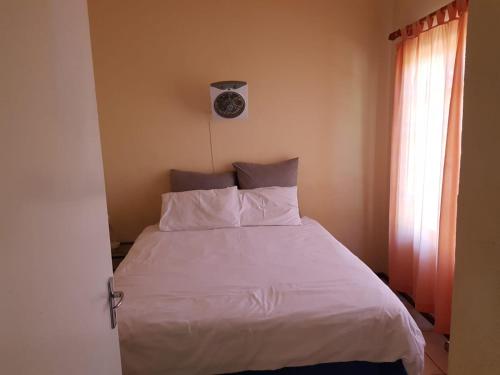 a bedroom with a white bed with a clock on the wall at Pendleberry Grove Holidays in Bela-Bela