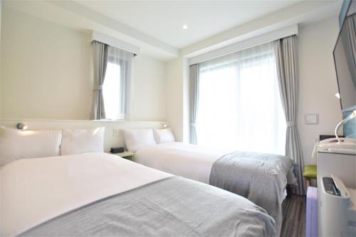 a hotel room with two beds and a window at ENKA NAMBA 1 HOTEL in Osaka