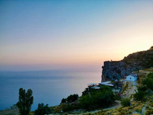 a small white house on a cliff overlooking the ocean at Elm pansiyon in Fethiye