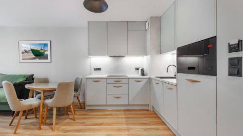 a kitchen with white cabinets and a table and chairs at Apartamenty Helski Brzeg in Hel