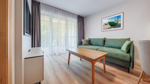 a living room with a green couch and a table at Apartamenty Helski Brzeg in Hel