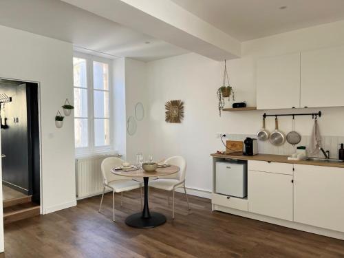 une cuisine avec des armoires blanches et une table et des chaises dans l'établissement Les Loges des Coteaux - Loge 1 - Luxury lodges with jacuzzi, à Blaye
