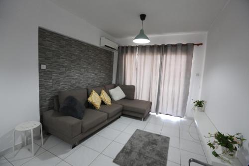 a living room with a couch and a brick wall at Near the Beach Holiday Apartment in Limassol
