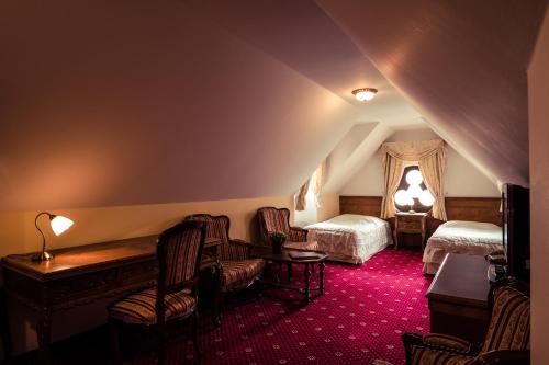 a hotel room with two beds and a table and chairs at Hotel Štekl in Hluboká nad Vltavou