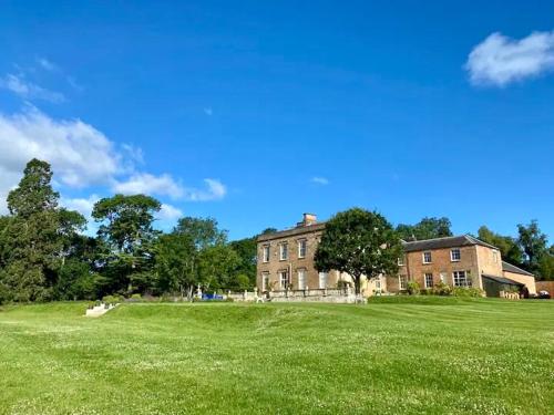 a large grassy field with a large brick building at Countryside bliss in Historic Hall in Burton Overy