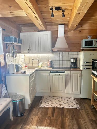 a kitchen with white appliances and wooden ceilings at Chata Nezábudka in Oščadnica