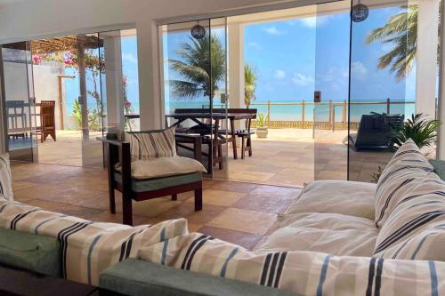 a living room with a couch and a view of the ocean at Muriú RN - Savage Beach House in Ceará-Mirim