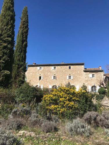 un grand bâtiment en briques avec deux arbres et des fleurs dans l'établissement Mas La Pleïade, à Vézénobres