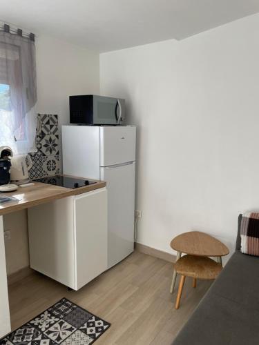 Elle comprend une petite cuisine équipée d'un réfrigérateur blanc et d'une table. dans l'établissement Dépendance 3 pièces Toulon, à Toulon