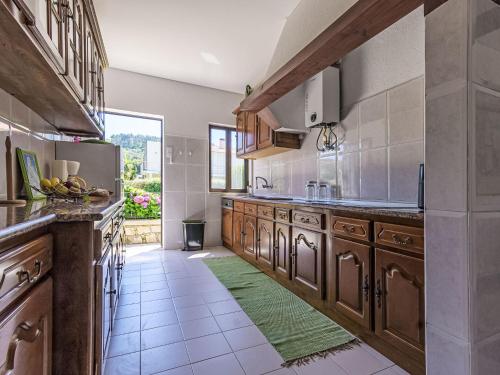 a large kitchen with wooden cabinets and a green rug at Holiday Home Do Condado by Interhome in Caminha