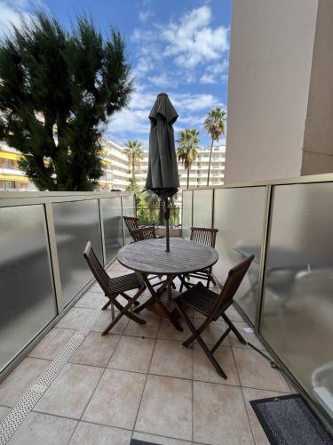 une table et des chaises sur un balcon avec un parasol dans l'établissement Cannes Croisette - Studio au calme avec terrasse, à Cannes