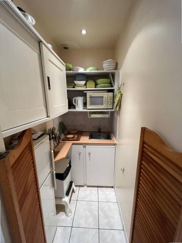 une petite cuisine avec des armoires blanches et un micro-ondes dans l'établissement Cannes Croisette - Studio au calme avec terrasse, à Cannes