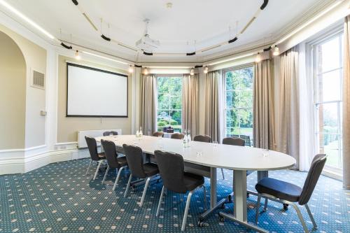 a meeting room with a white table and chairs at Sedgebrook Hall in Northampton