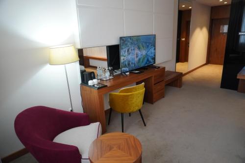 a room with a tv and a desk with a chair at Hotel Mepas in Mostar