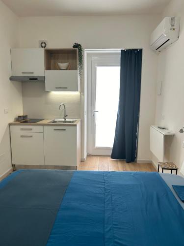 1 dormitorio con 1 cama azul y cocina en Dimora Claramare, en Marzamemi