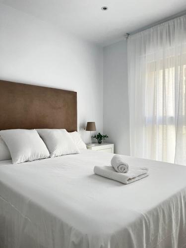 a white bed with a towel on it with a window at Dailos Ávila in Ávila