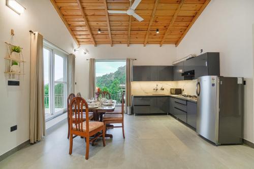 a kitchen with a table and chairs and a refrigerator at SaffronStays Bourbon in Bhīm Tāl