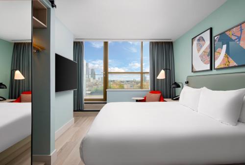 a hotel room with a large bed and a large window at Hyatt Place London City East in London