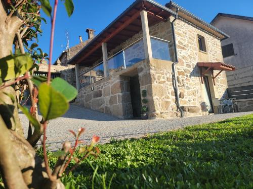 a large stone house with a large window at A Nossa Casinha in Arcos de Valdevez
