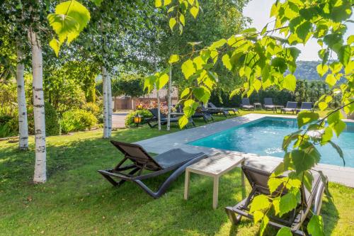 a pool with two chairs and a table next to it at Hotel Calitxo in Molló