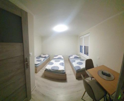 a room with four beds and a table and a table and chairs at Pokoje gościnne Kamila in Jarosławiec