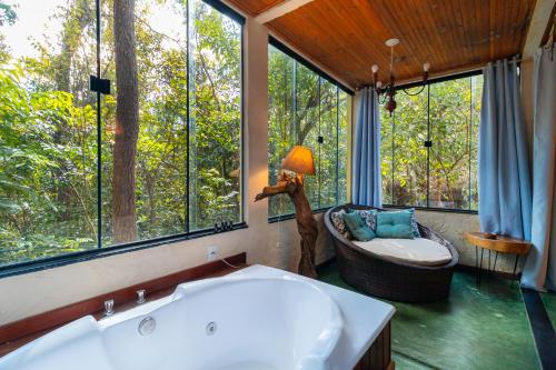 a bathroom with a tub and a chair and windows at Pousada Do Lado de Lá in Pirenópolis
