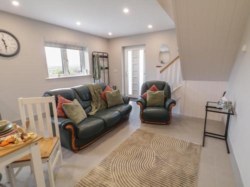 a living room with a leather couch and two chairs at Ard Na Ghaoithe in Loughanure