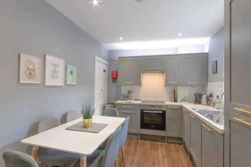 a kitchen with gray cabinets and a table and chairs at Stylish home close to the BEACH By Adliv in Margate