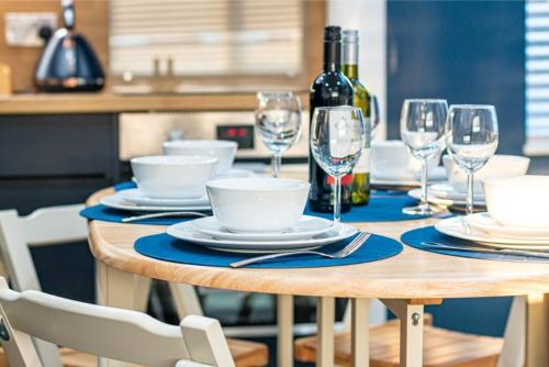 a wooden table with plates and wine glasses on it at Rooftop Terrace with Harbour Views By Adliv in Ramsgate