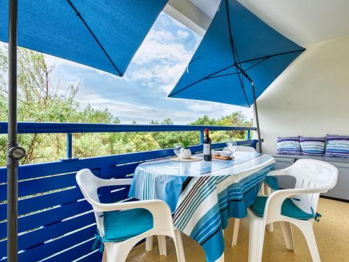une table et des chaises sur un balcon avec des parasols bleus dans l'établissement Apartment Bleu Marine-12 by Interhome, à Lacanau-Océan