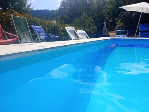 a blue swimming pool with chairs and an umbrella at Il Podere di Massi in Barberino di Mugello