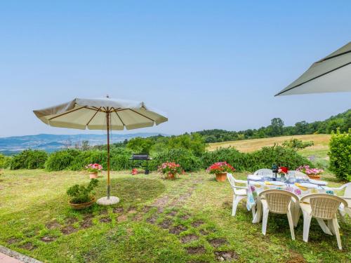 a table and chairs with an umbrella in the grass at Apartment Bellavista-1 by Interhome in Castellina Marittima