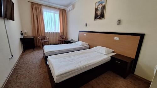 a hotel room with two beds and a desk at Optima Odesa in Odesa