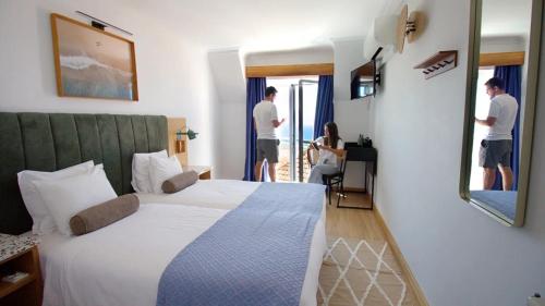 a hotel room with a bed and two people standing in the window at WOT Ericeira in Ericeira