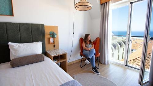 a woman sitting in a chair in a hotel room at WOT Ericeira in Ericeira
