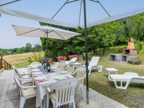a table with white chairs and an umbrella at Apartment Bellavista-2 by Interhome in Castellina Marittima