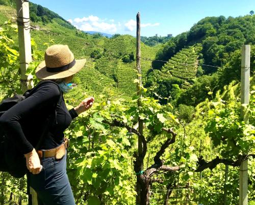 a woman in a hat looking at a vineyard at Villa Abbazia Relais & Chateaux in Follina